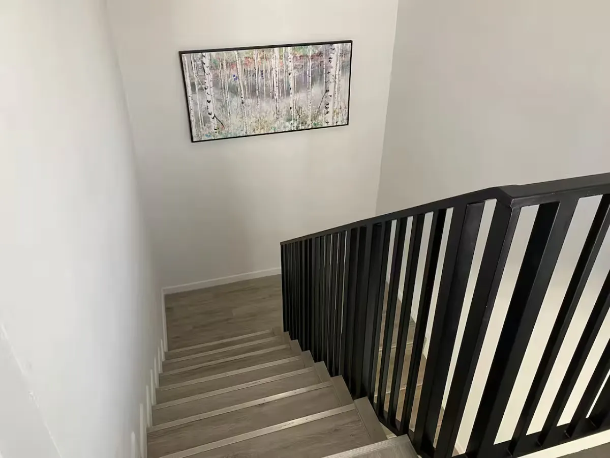 A serene staircase area with framed artwork on the wall, suggesting a well-kept communal space. The perspective hints at movement through the building, such as arriving, departing, or heading to amenities.