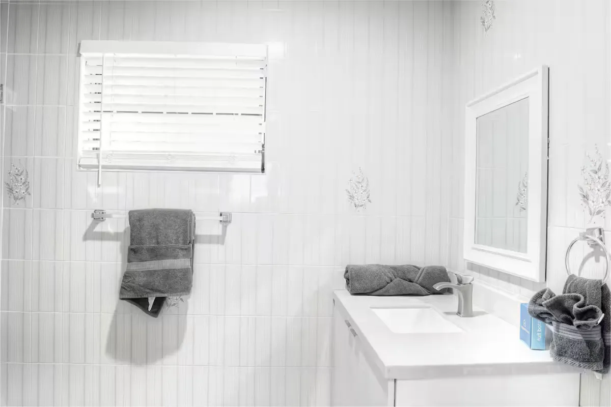 A modern bathroom featuring plush towels, a large mirror, and a sleek sink, bathed in gentle lighting that communicates tranquility and rejuvenation. The space feels fresh and welcoming, perfect for evening routines after a night out.