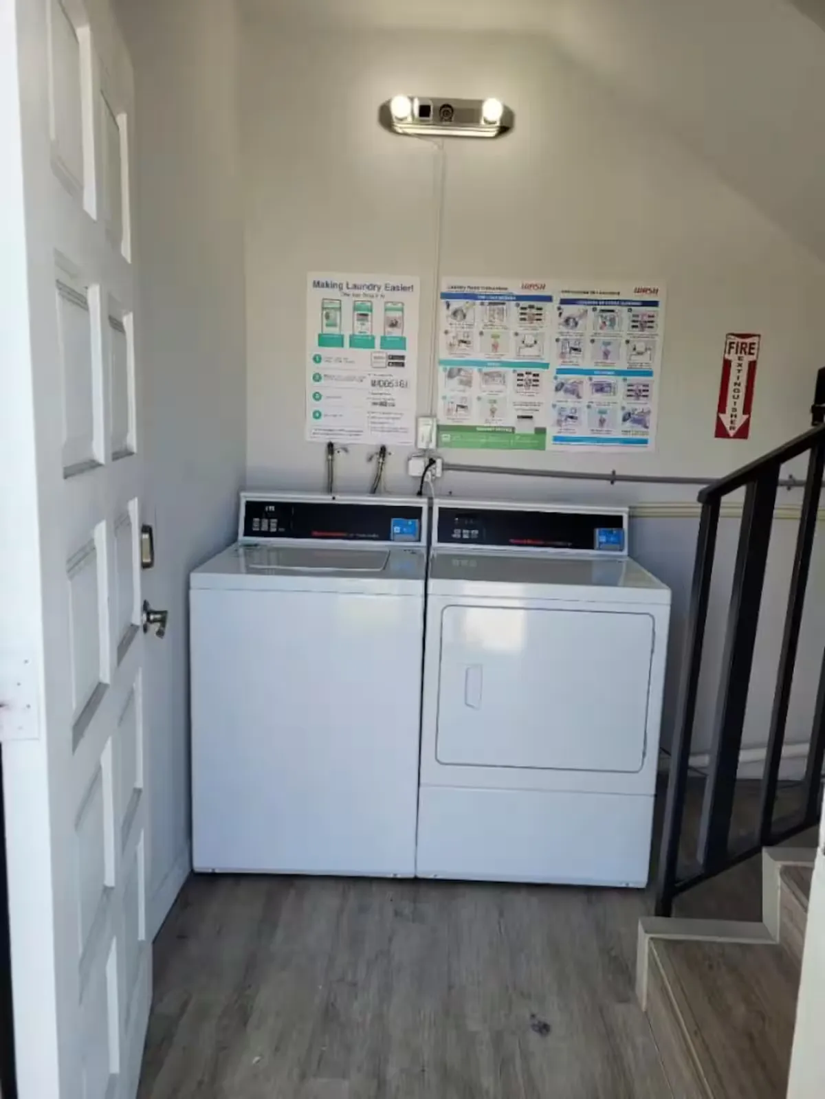 The photo features a practical laundry area with a washing machine, clothes dryer, and clear instructional posters on the wall. The space is well-lit and organized, emphasizing convenience and ease of use for guests staying longer or traveling light.